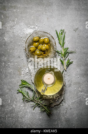 Olives et huile d'olive avec des branches de romarin. sur un fond en pierre. Banque D'Images