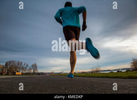 Un portrait d'un coureur au crépuscule le long d'un sentier à côté du Puget Sound à Seattle, WA. Banque D'Images