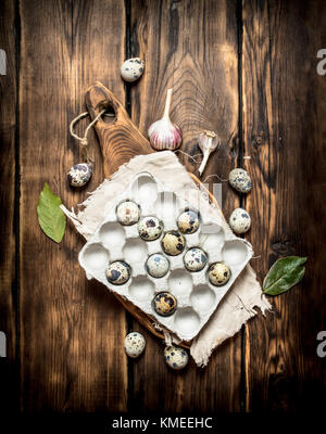 Des oeufs de cailles dans une boîte avec feuilles de laurier sur une table en bois. Banque D'Images