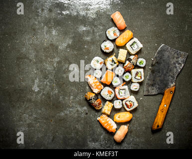 Divers rouleaux de sushi japonais avec une hache pour couper. sur la table de pierre. Banque D'Images