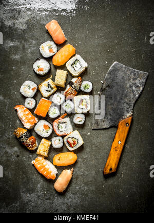 Divers rouleaux de sushi japonais avec une hache pour couper. sur la table de pierre. Banque D'Images