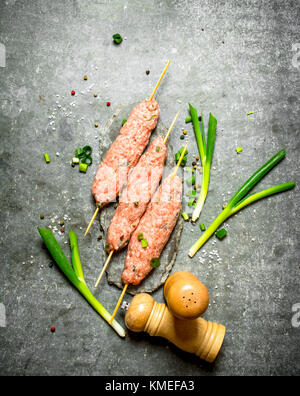 Les brochettes sur des brochettes en bois brut d'oignons verts. sur la table de pierre. Banque D'Images