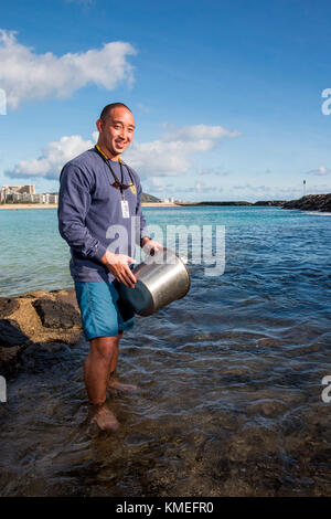 Wataru Kumagai, de la Direction de l'eau propre du Département de la santé de l'État d'Hawaï, démontre l'échantillonnage d'eau des plages hawaïennes à la plage d'Ala Moana à Honolulu à l'aide d'instruments tels qu'un turbidimètre. Pour la portée complète des lectures, des travaux de laboratoire ont été effectués hors site. Banque D'Images