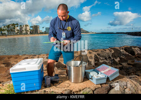 Wataru Kumagai, de la Direction de l'eau propre du Département de la santé de l'État d'Hawaï, démontre l'échantillonnage d'eau des plages hawaïennes à la plage d'Ala Moana à Honolulu à l'aide d'instruments tels qu'un turbidimètre. Pour la portée complète des lectures, des travaux de laboratoire ont été effectués hors site. Banque D'Images