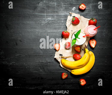Dessert avec un smoothie fraise , banane et menthe. sur la table en bois noir. Banque D'Images