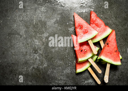 Tranches de melon sur des bâtonnets de bois. sur la table de pierre. Banque D'Images