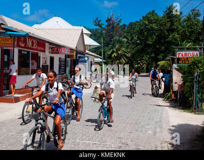 Les élèves sur bicyclettes dans la rue principale de la Passe, La Digue, Seychelles, océan Indien, Afrique Banque D'Images