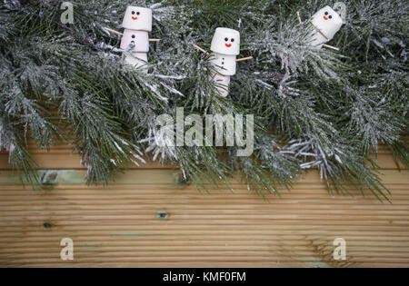 Image arbre Noël photographie avec garland saupoudré de neige sur fond de bois naturel rustique avec copie espace et les guimauves en forme de bonhomme Banque D'Images