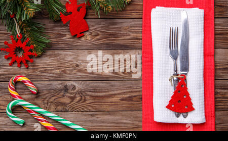 Table de noël place avec fourchette et couteau, jouets de Noël - Décoration de sapin rouge, deux cannes à sucette et Noël des branches de pins. Banque D'Images