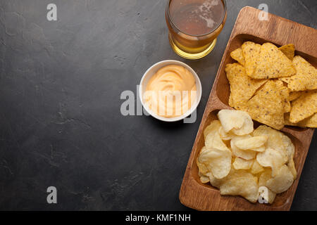Bière en verres sur la table en béton.La bière et les en-cas sont des frites et des nachos dans un bol en bois avec une pâte au fromage. Vue de dessus.Copier l'espace.Buvez et Banque D'Images