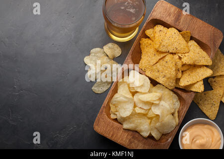 Bière en verres sur la table en béton.La bière et les en-cas sont des frites et des nachos dans un bol en bois avec une pâte au fromage. Vue de dessus.Copier l'espace.Buvez et Banque D'Images