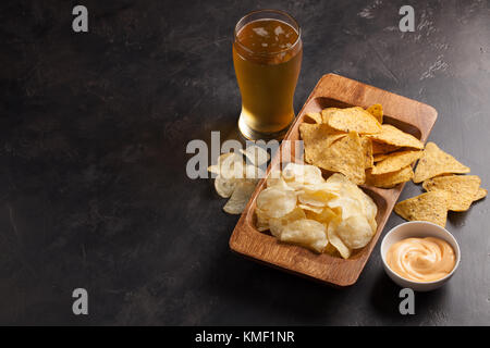 Bière en verres sur la table en béton.La bière et les en-cas sont des frites et des nachos dans un bol en bois avec une pâte au fromage. Vue de dessus.Copier l'espace.Buvez et Banque D'Images
