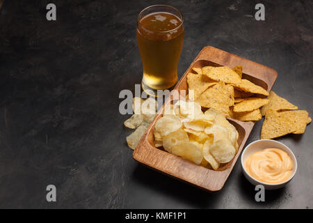 Bière en verres sur la table en béton.La bière et les en-cas sont des frites et des nachos dans un bol en bois avec une pâte au fromage. Vue de dessus.Copier l'espace.Buvez et Banque D'Images