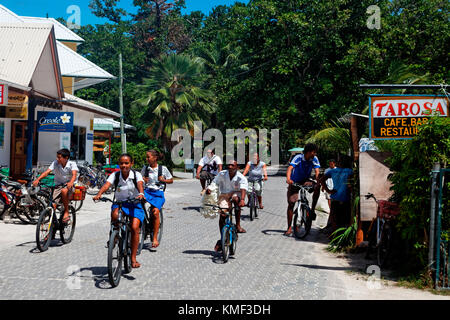 Les élèves sur bicyclettes dans la rue principale de la Passe, La Digue, Seychelles, océan Indien, Afrique Banque D'Images