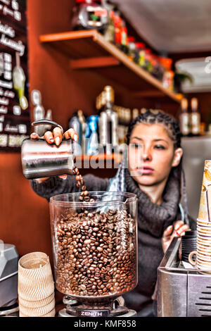 Latin American girl - grains de café barista met dans une machine à café Banque D'Images