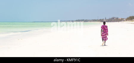 Guerrier masaï marche sur la plage de sable tropicale. paje, Zanzibar, Tanzanie. Banque D'Images