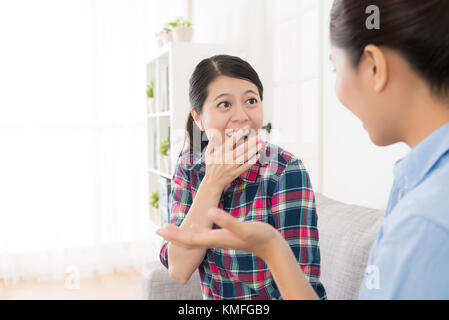 Belle cheerful girl en tenant l'humour blague histoire pour sa soeur dans la salle de séjour et heureux profiter de temps libre ensemble. selective focus photo. Banque D'Images