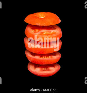 Concept créatif avec flying tomato. tranches de tomate rouge isolé sur fond noir. Légèreté légumes flottant dans l'air. Banque D'Images
