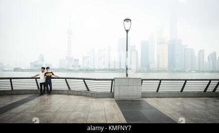 SHANGHAI, CHINE - 6 JUN 2015 : Deux jeunes hommes posent pour une photo selfies en face du quartier des affaires de Shanghai skyline. de tout le fleuve Huangpu Banque D'Images