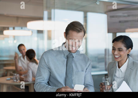 Businessman and businesswoman using cell phone in office Banque D'Images