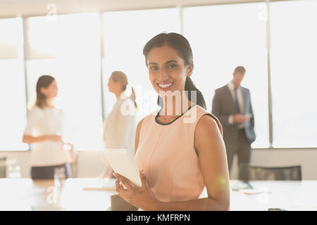 Portrait femme d'affaires souriante et confiante avec une tablette numérique dans la salle de conférence Banque D'Images