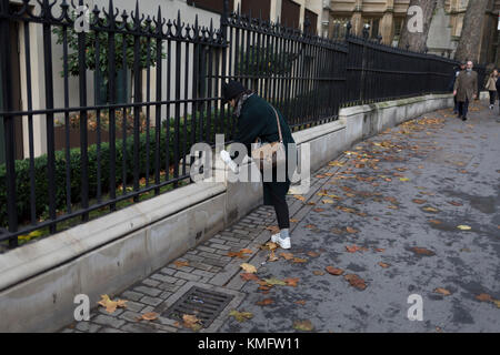 Une dame se penche pour attacher les lacets de ses formateurs, à New Fetter Lane, le 27 novembre 2017, dans la ville de Londres, en Angleterre. Banque D'Images