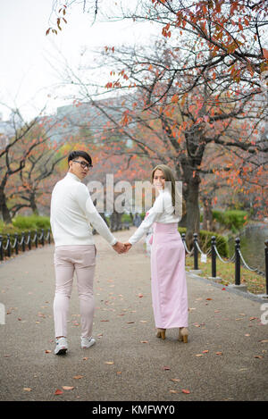 Jeune couple japonais walking together in autumn park Banque D'Images