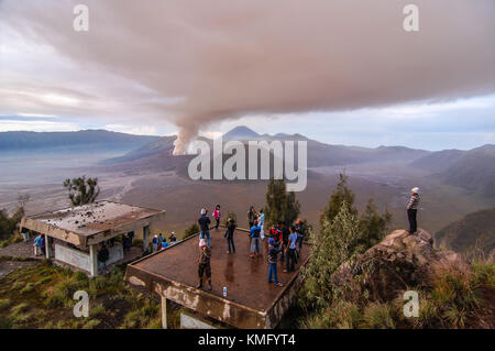 Les touristes apprécient la vue pendant l'éruption de Bromo à distance de sécurité. Banque D'Images