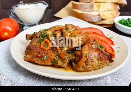 Ragoût de morceaux de lapin avec la tomate fraîche sur une plaque en céramique sur un fond de bois sombre. Menu diététique. Banque D'Images