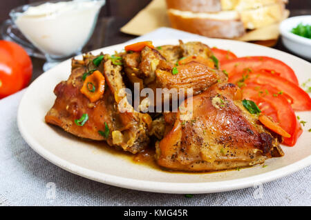 Ragoût de morceaux de lapin avec la tomate fraîche sur une plaque en céramique sur un fond de bois sombre. Menu diététique. Banque D'Images