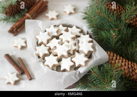 Cannelle cookies star dans une jolie boîte sur fond de branches de sapin, bâtons de cannelle et les cônes. Banque D'Images