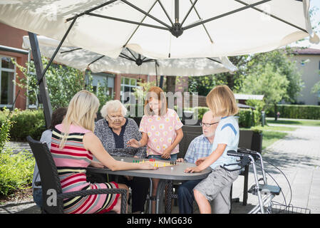 Multi-generation family playing board game à nursing home Banque D'Images