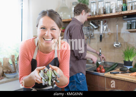 Couple preparing food, woman holding asparagus Banque D'Images