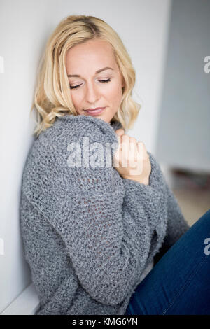 Beautiful woman leaning against wall avec les yeux fermé Banque D'Images