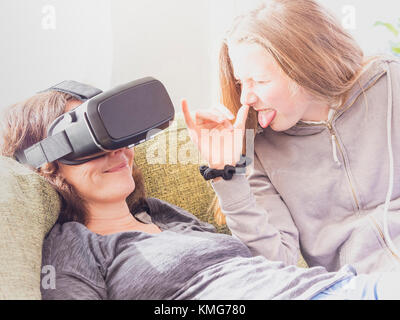 Une fille espiègle avec sa mère à l'aide d'un casque de réalité virtuelle Banque D'Images