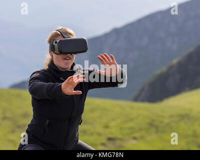 Femme pratiquant des mouvements de karaté avec des lunettes de réalité virtuelle sur la montagne Banque D'Images