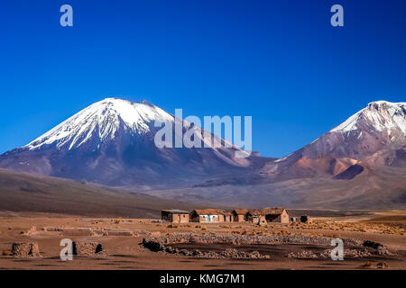 Maisons et maisons abandonnées au pied de deux énormes volcans Nevado Sajama, Parinacota et dans le parc national, la Bolivie Banque D'Images