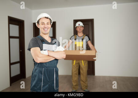 Les travailleurs de deux hommes en uniforme dans la maison propre arrière-plan de la salle Banque D'Images