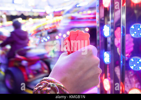 Main femme avec un fistfull de jetons pour parc d'enfants. piste voitures ride Scène de nuit Banque D'Images