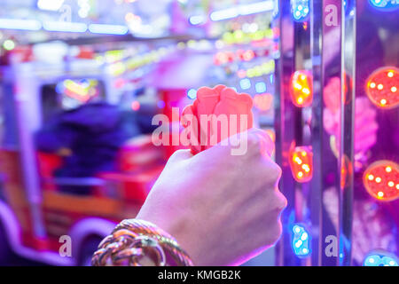 Main femme avec un fistfull de jetons pour parc d'enfants. piste voitures ride Scène de nuit Banque D'Images