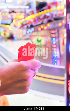 Main femme avec un fistfull de jetons pour parc d'enfants. piste voitures ride Scène de nuit Banque D'Images