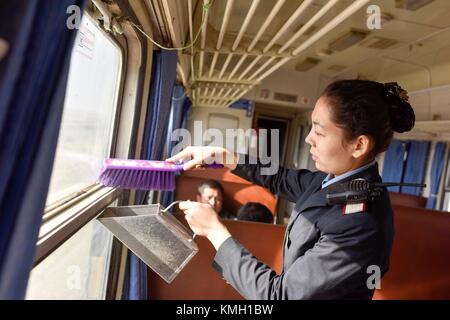 (171209) -- URUMQI, Dec. 9, 2017 (Xinhua) -- le préposé Subinuer Tayeer nettoie la poussière de sable sur le train n° 5809 reliant Kashgar et Hotan dans la région autonome ouïgur du Xinjiang, au nord-ouest de la Chine, 24 novembre 2017. La ligne ferroviaire de 485 km reliant deux grandes villes oasis, Kashgar et Hotan, traverse certaines des zones les plus reculées du Xinjiang et a transformé la vie dans le désert depuis son lancement en 2011. C'est le premier et le seul chemin de fer de Hotan, via le chemin de fer la préfecture sous-développée est reliée au reste du réseau ferroviaire du pays, qui compte 22 000 km de lignes ferroviaires à grande vitesse. Pauvre tra Banque D'Images