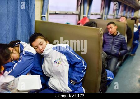 (171209) -- URUMQI, Dec. 9, 2017 (Xinhua) -- les élèves du collège de Kashgar no 6 reposent sur le train no 5809 reliant Kashgar et Hotan dans la région autonome ouïgur du Xinjiang, au nord-ouest de la Chine, 24 novembre 2017. La ligne ferroviaire de 485 km reliant deux grandes villes oasis, Kashgar et Hotan, traverse certaines des zones les plus reculées du Xinjiang et a transformé la vie dans le désert depuis son lancement en 2011. C'est le premier et le seul chemin de fer de Hotan, via le chemin de fer la préfecture sous-développée est reliée au reste du réseau ferroviaire du pays, qui compte 22 000 km de lignes ferroviaires à grande vitesse. Poo Banque D'Images