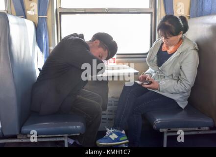 (171209) -- URUMQI, Dec. 9, 2017 (Xinhua) -- des passagers sont vus sur le train n° 5809 reliant Kashgar et Hotan dans la région autonome ouïgur du Xinjiang, au nord-ouest de la Chine, 24 novembre 2017. La ligne ferroviaire de 485 km reliant deux grandes villes oasis, Kashgar et Hotan, traverse certaines des zones les plus reculées du Xinjiang et a transformé la vie dans le désert depuis son lancement en 2011. C'est le premier et le seul chemin de fer de Hotan, via le chemin de fer la préfecture sous-développée est reliée au reste du réseau ferroviaire du pays, qui compte 22 000 km de lignes ferroviaires à grande vitesse. Infrastructure de transport médiocre h Banque D'Images