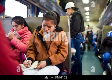 (171209) -- URUMQI, Dec. 9, 2017 (Xinhua) -- étudiants de Kashgar No. 6 étude du collège sur le train No. 5809 reliant Kashgar et Hotan dans la région autonome ouïgur du Xinjiang, au nord-ouest de la Chine, 24 novembre 2017. La ligne ferroviaire de 485 km reliant deux grandes villes oasis, Kashgar et Hotan, traverse certaines des zones les plus reculées du Xinjiang et a transformé la vie dans le désert depuis son lancement en 2011. C'est le premier et le seul chemin de fer de Hotan, via le chemin de fer la préfecture sous-développée est reliée au reste du réseau ferroviaire du pays, qui compte 22 000 km de lignes ferroviaires à grande vitesse. Poo Banque D'Images