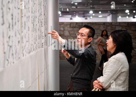 Paris, France. Dec 11, 2017. Les visiteurs d'admirer un morceau de calligraphie chinoise créé par Zhang Xuguang à l'Organisation des Nations Unies pour l'éducation, la science et la culture (UNESCO), siège à Paris, France, le 11 décembre, 2017. 'L'Aspirant à la paix--Zhang Xuguang Cursive de l'Exhibition' le coup d'ici lundi. Environ 50 pièces de calligraphie chinoise de Zhang Xuguang salue les visiteurs jusqu'au 16 décembre. Crédit : Chen Yichen/Xinhua/Alamy Live News Banque D'Images