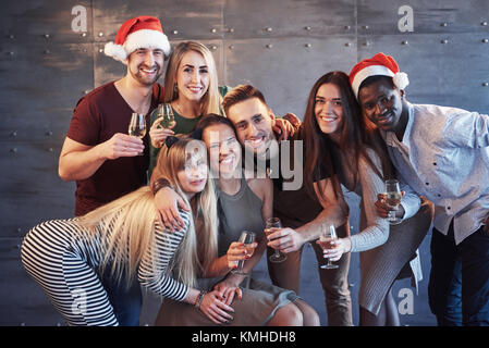 Nouvelle année s'en vient ! Groupe de jeunes gens joyeux multiethnique dans Santa hats sur la partie émotionnelle, posant les gens vie concept. Banque D'Images
