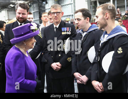 La reine Elizabeth II parle aux membres de l'équipage du navire, lors de la mise en service du HMS Queen Elizabeth, le plus grand et le plus puissant navire de guerre, dans la Royal Navy Fleet à Portsmouth Naval Base. Banque D'Images