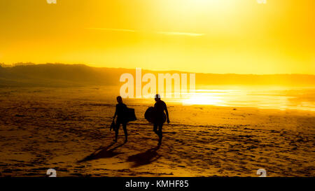 Surfers quitter Peniche beach at sunset Banque D'Images