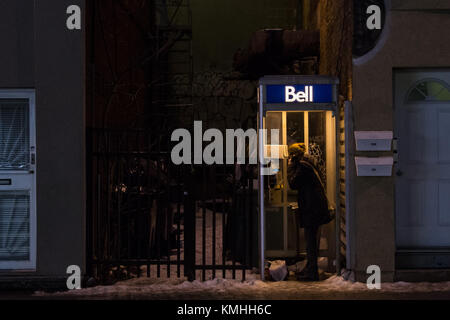 Montréal, Canada - le 24 décembre 2016 : femme à l'aide d'un téléphone payant de Bell Canada à Montréal dans la soirée sous le poids de la neige. Bell Canada est l'un des principaux p Banque D'Images